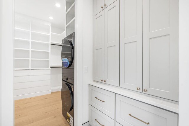 spacious closet featuring light hardwood / wood-style flooring and stacked washer / drying machine