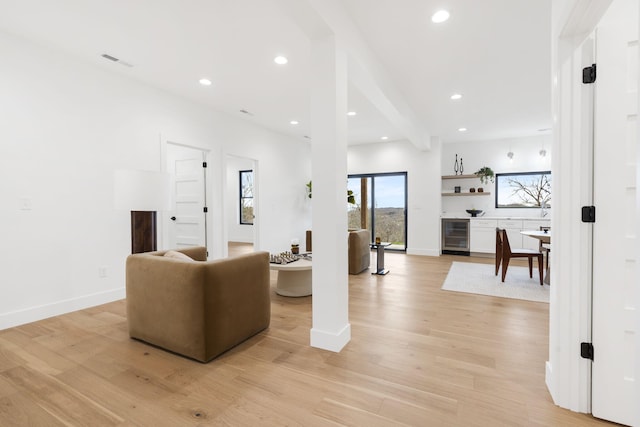 living room featuring beamed ceiling, wine cooler, and light hardwood / wood-style flooring