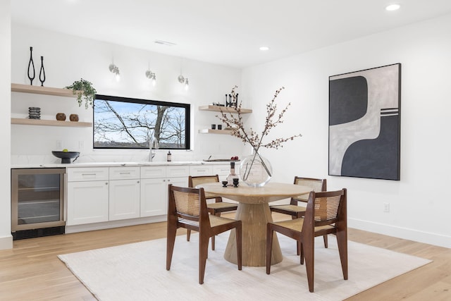 dining space featuring light hardwood / wood-style floors, beverage cooler, and sink