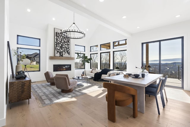 dining area with beamed ceiling, high vaulted ceiling, light hardwood / wood-style floors, and an inviting chandelier