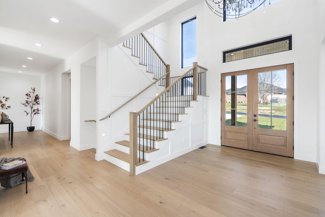 entrance foyer featuring french doors, an inviting chandelier, and light hardwood / wood-style flooring