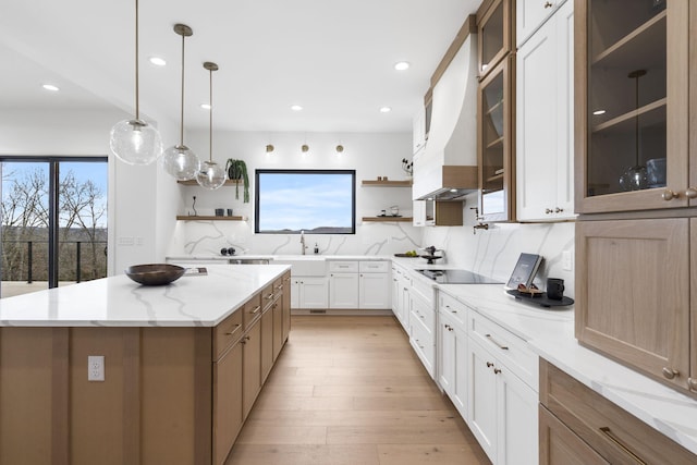 kitchen with white cabinetry, backsplash, pendant lighting, a kitchen island, and custom range hood