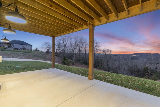 patio terrace at dusk featuring a lawn