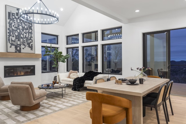 dining room featuring a notable chandelier, light wood-type flooring, and vaulted ceiling