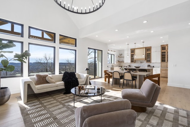 living room featuring light hardwood / wood-style floors, high vaulted ceiling, and an inviting chandelier