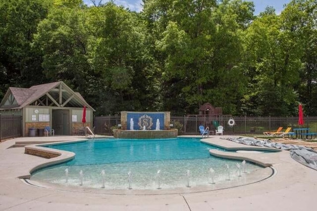 view of swimming pool featuring pool water feature, an outbuilding, and a patio