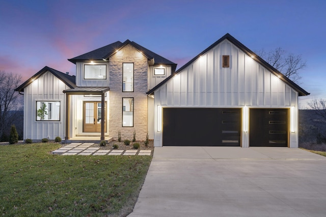 modern farmhouse featuring a garage, a yard, and french doors