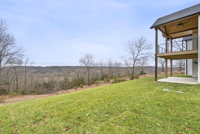 view of yard featuring a patio area, ceiling fan, and a balcony