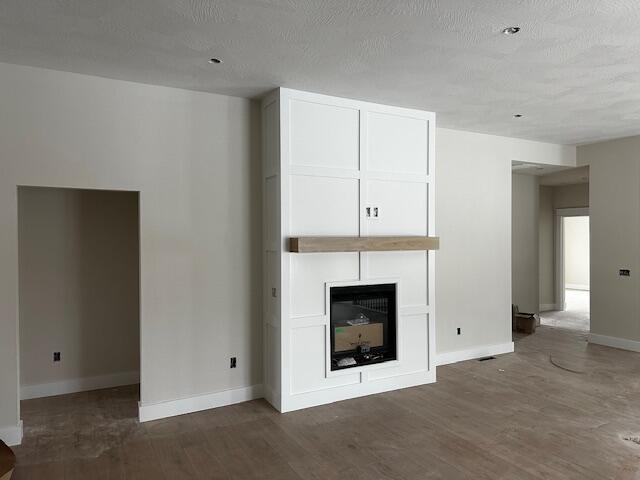 unfurnished living room with dark hardwood / wood-style floors, a large fireplace, and a textured ceiling