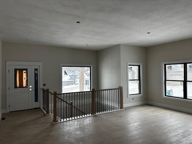 unfurnished room with light hardwood / wood-style flooring and a textured ceiling