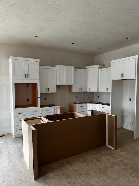 kitchen with white cabinetry, a center island, and a textured ceiling