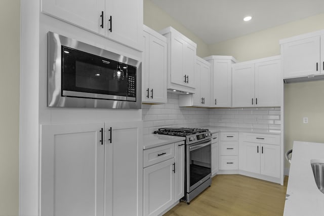 702 S Thornridge Dr, Springfield, MO 65809 - kitchen featuring gas range, built in microwave, white cabinetry, decorative backsplash, and light wood-style flooring