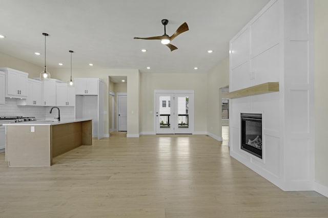 702 S Thornridge Dr, Springfield, MO 65809 - kitchen with a ceiling fan, light wood-type flooring, backsplash, white cabinetry, and a large fireplace