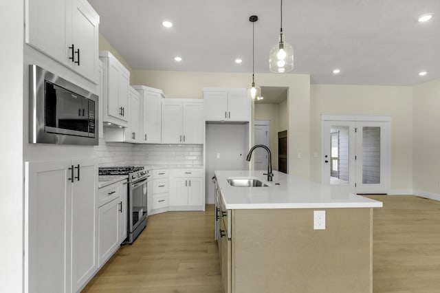 702 S Thornridge Dr, Springfield, MO 65809 - kitchen with appliances with stainless steel finishes, a sink, light wood-style flooring, backsplash, and a kitchen island with sink