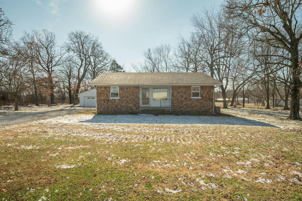 view of side of home featuring covered porch, a garage, an outdoor structure, and a lawn