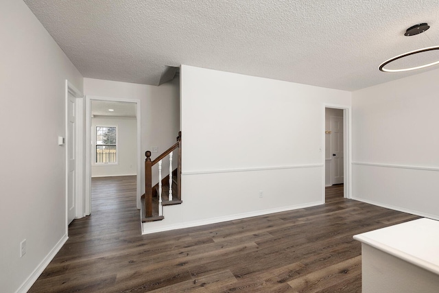 spare room featuring a textured ceiling and dark wood-type flooring