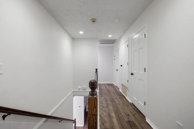 corridor with a textured ceiling and dark hardwood / wood-style floors