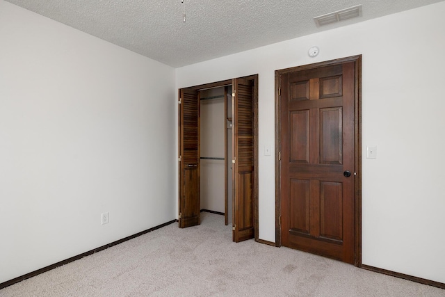 unfurnished bedroom with light colored carpet, a textured ceiling, and a closet