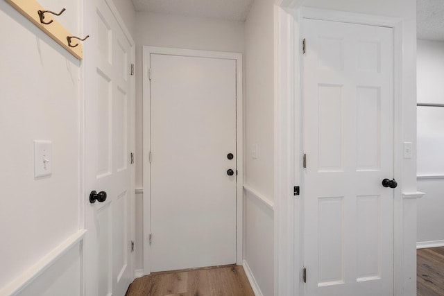 hall with hardwood / wood-style floors and a textured ceiling