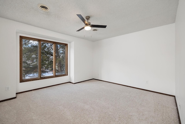 empty room with ceiling fan, light colored carpet, and a textured ceiling