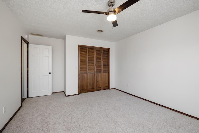 unfurnished bedroom featuring a textured ceiling, ceiling fan, light carpet, and a closet