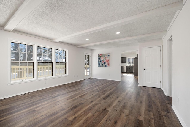 unfurnished living room featuring beamed ceiling, dark hardwood / wood-style floors, and a textured ceiling