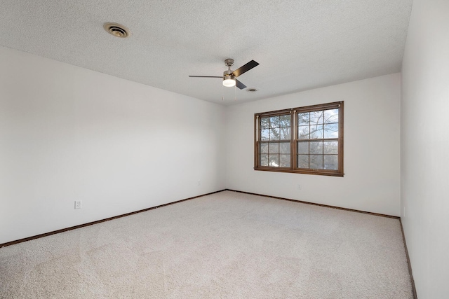 spare room with ceiling fan, light colored carpet, and a textured ceiling