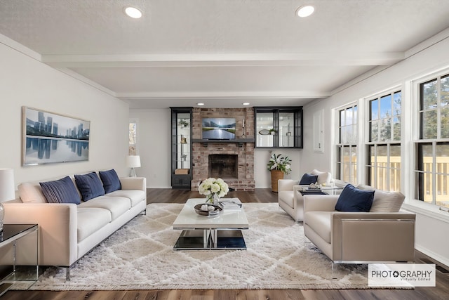 living room featuring beam ceiling, wood-type flooring, and a fireplace