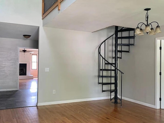 staircase with hardwood / wood-style floors and ceiling fan with notable chandelier