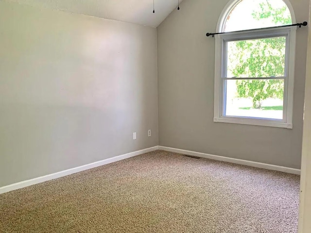 spare room with carpet floors, vaulted ceiling, and plenty of natural light