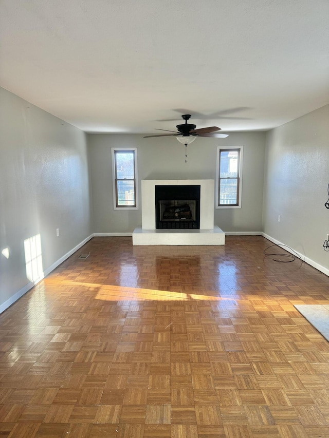 unfurnished living room featuring parquet flooring, plenty of natural light, and ceiling fan