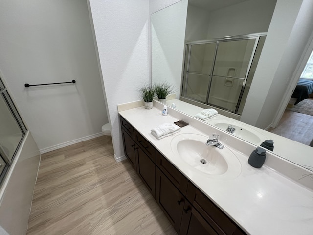 bathroom with hardwood / wood-style floors, vanity, toilet, and a shower with shower door