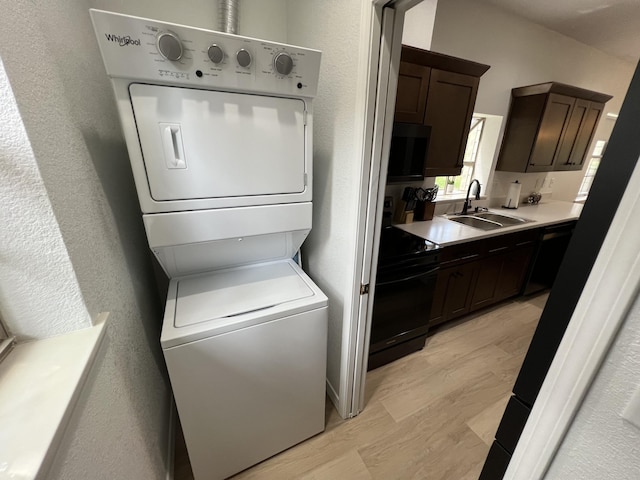 clothes washing area featuring light hardwood / wood-style floors, sink, and stacked washer / dryer