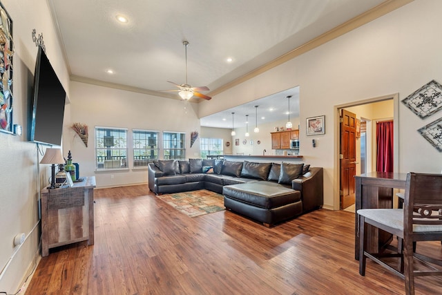 living room featuring ceiling fan, hardwood / wood-style floors, a high ceiling, and ornamental molding