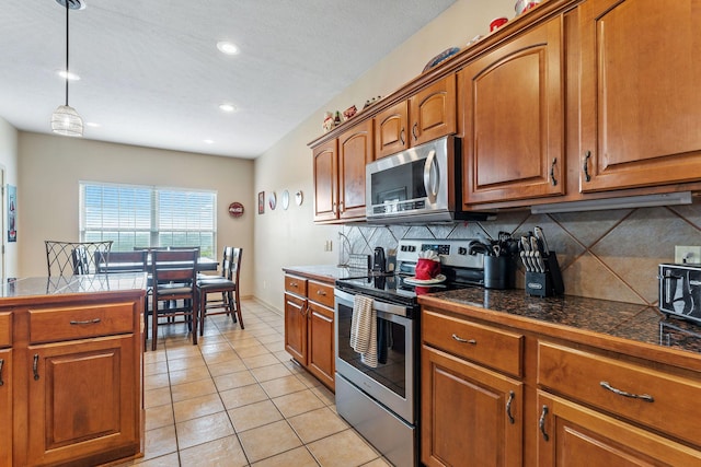 kitchen with pendant lighting, light tile patterned flooring, appliances with stainless steel finishes, and tasteful backsplash