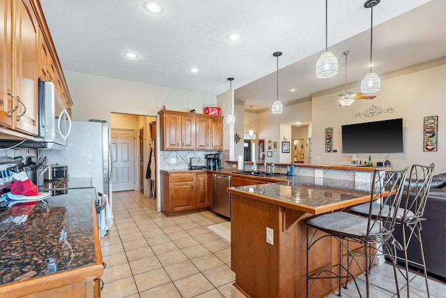 kitchen featuring pendant lighting, a kitchen breakfast bar, sink, stainless steel dishwasher, and kitchen peninsula