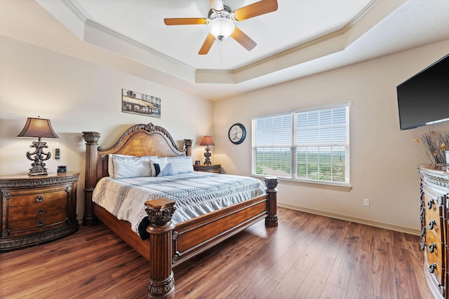 bedroom featuring dark hardwood / wood-style flooring, a tray ceiling, ceiling fan, and crown molding