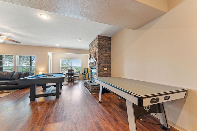 playroom featuring ceiling fan, dark hardwood / wood-style floors, a textured ceiling, a fireplace, and pool table