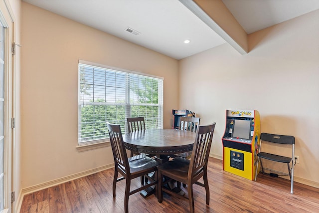 dining room featuring beamed ceiling, a healthy amount of sunlight, and hardwood / wood-style flooring