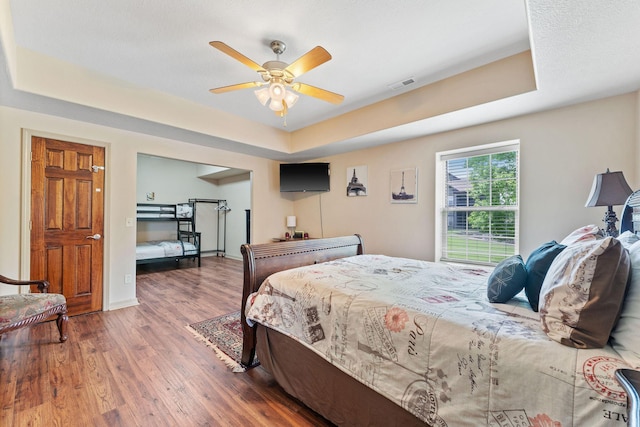 bedroom featuring a raised ceiling, ceiling fan, and hardwood / wood-style floors