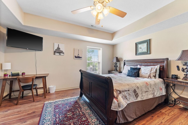 bedroom featuring hardwood / wood-style flooring, ceiling fan, and a tray ceiling