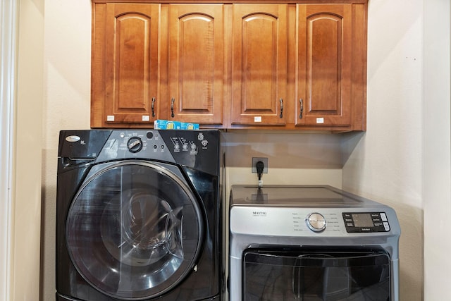 clothes washing area with separate washer and dryer and cabinets