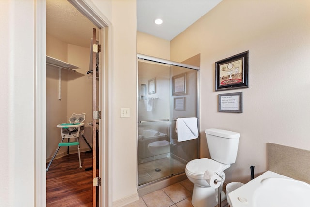 bathroom featuring tile patterned flooring, toilet, and a shower with door