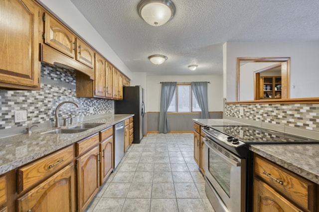 kitchen with sink, backsplash, appliances with stainless steel finishes, and a textured ceiling