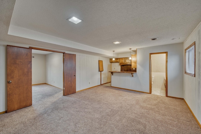 unfurnished living room with light colored carpet and a textured ceiling