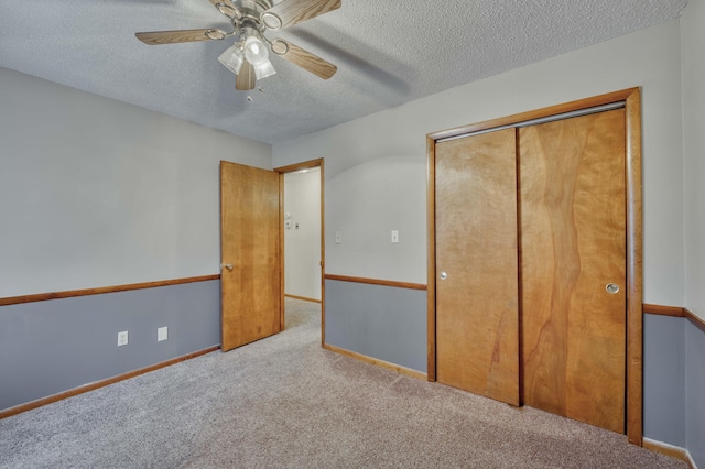 unfurnished bedroom featuring a closet, ceiling fan, a textured ceiling, and light carpet