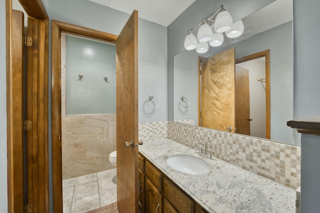 bathroom with tile patterned floors, toilet, tile walls, and vanity