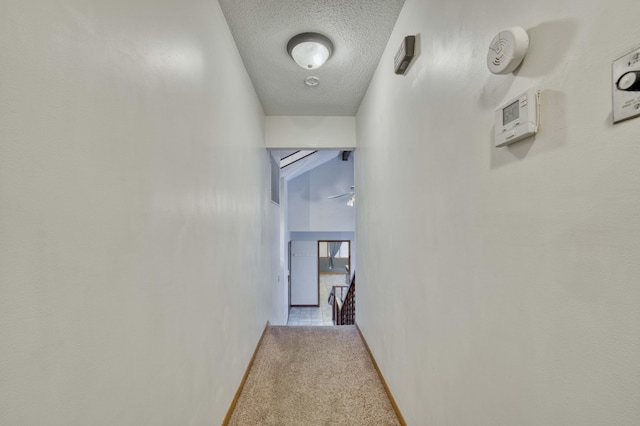 hallway featuring light colored carpet and a textured ceiling