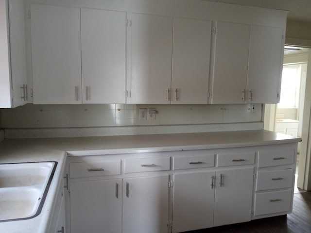 kitchen with light countertops, white cabinetry, and a sink