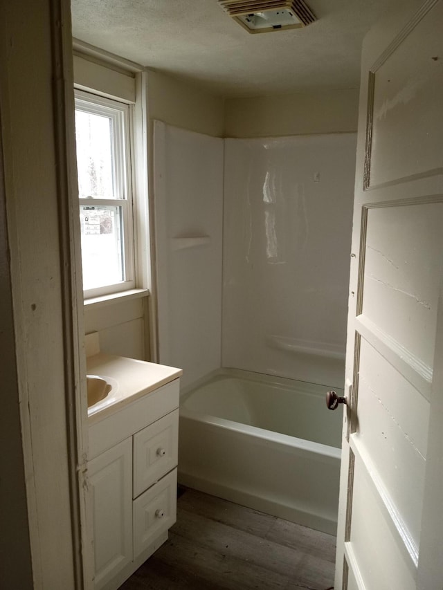 bathroom featuring visible vents, shower / bathing tub combination, vanity, a textured ceiling, and wood finished floors